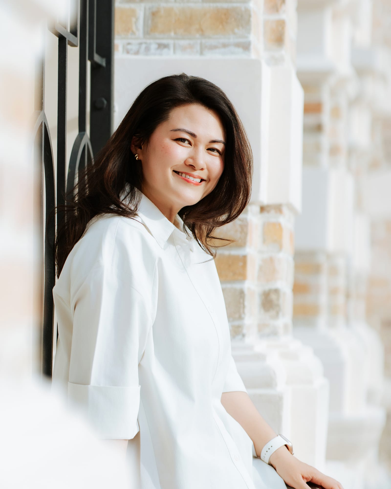 Chan Quin Er laughing, in a white shirt, leaning against a white pillar.
