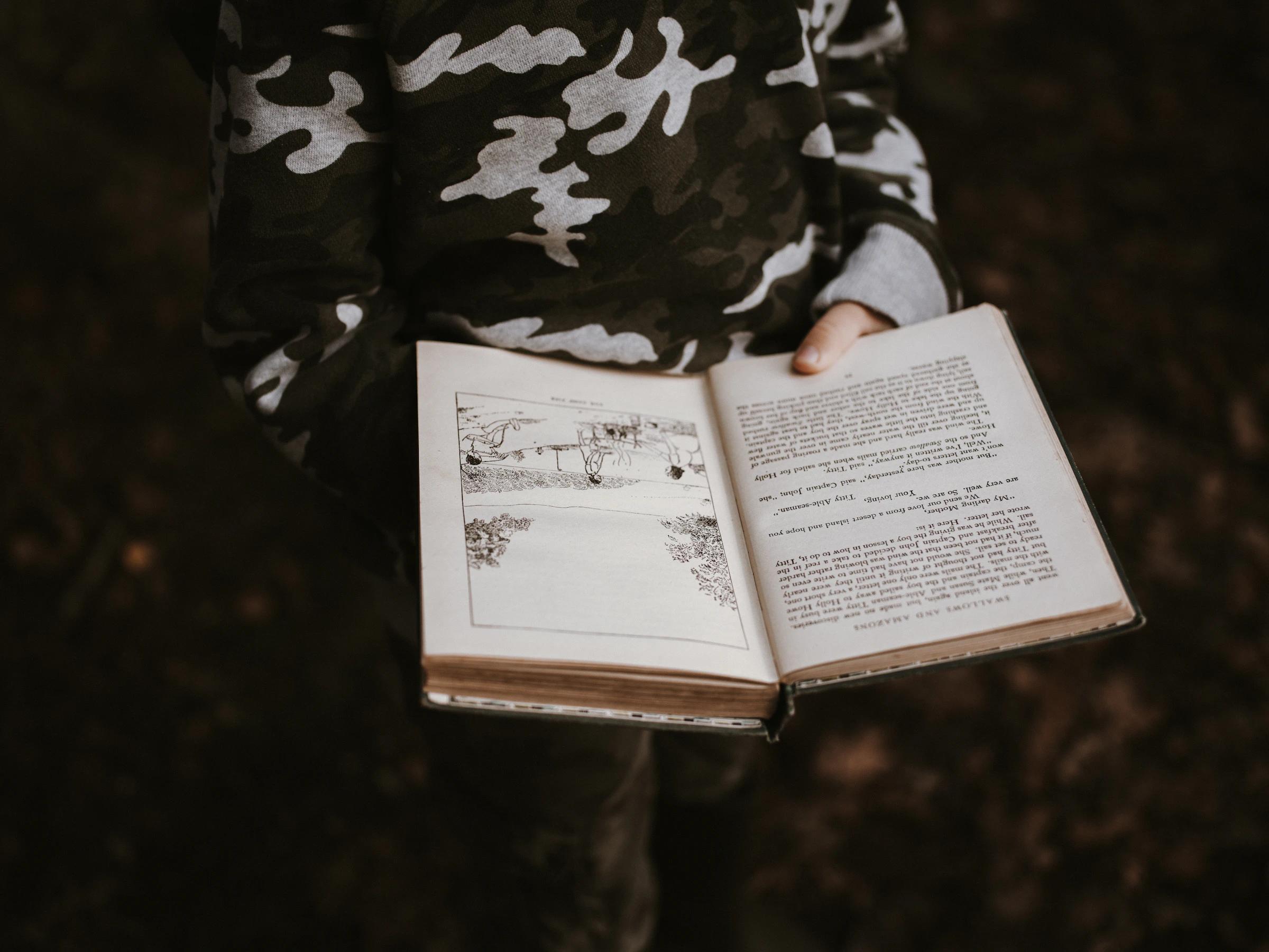 A child's hands holding open an old illustrated book.